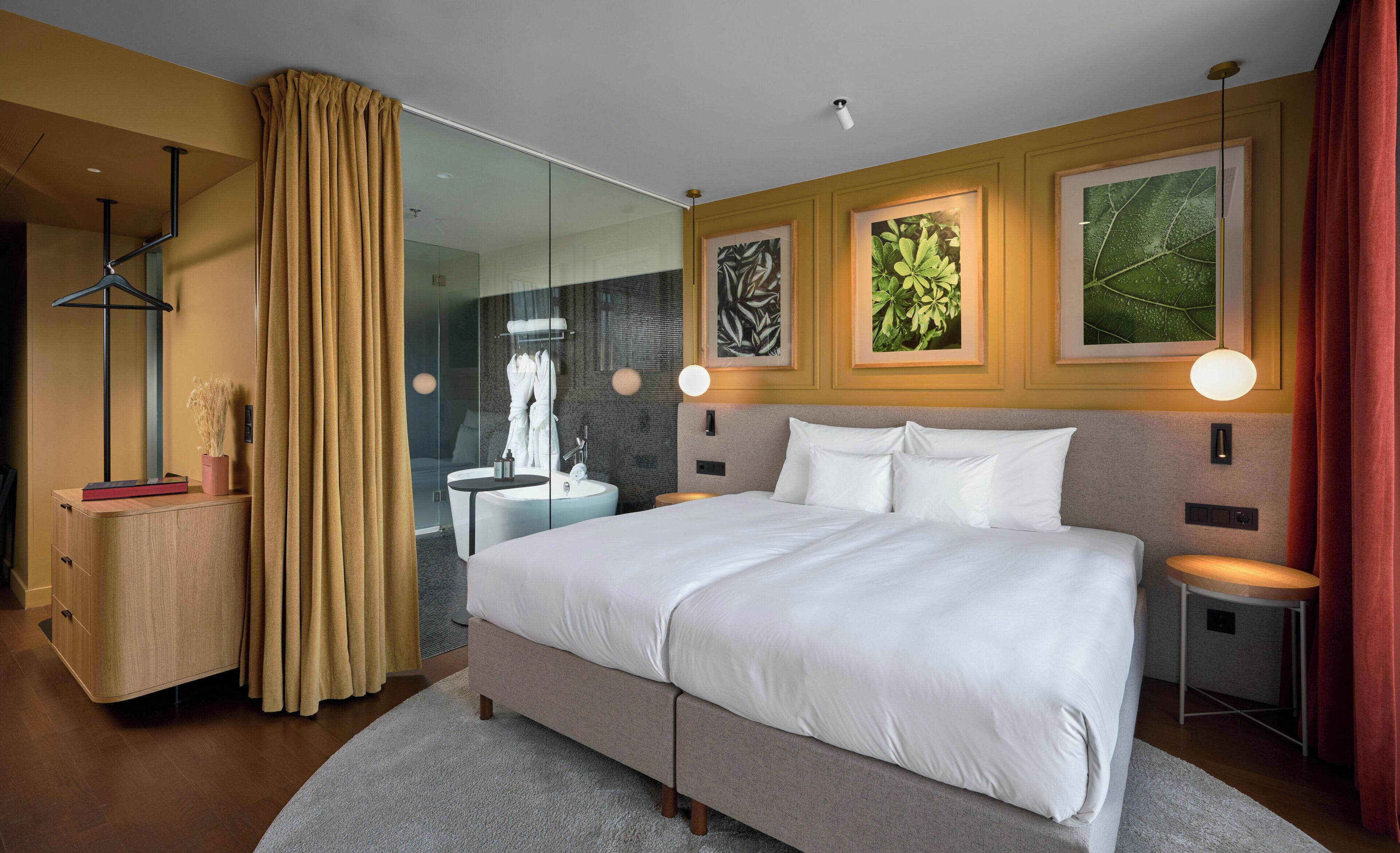 Een moderne hotelkamer met een groot bed, nachtkastjes, een douchecabine van glas en kunst aan de muur.