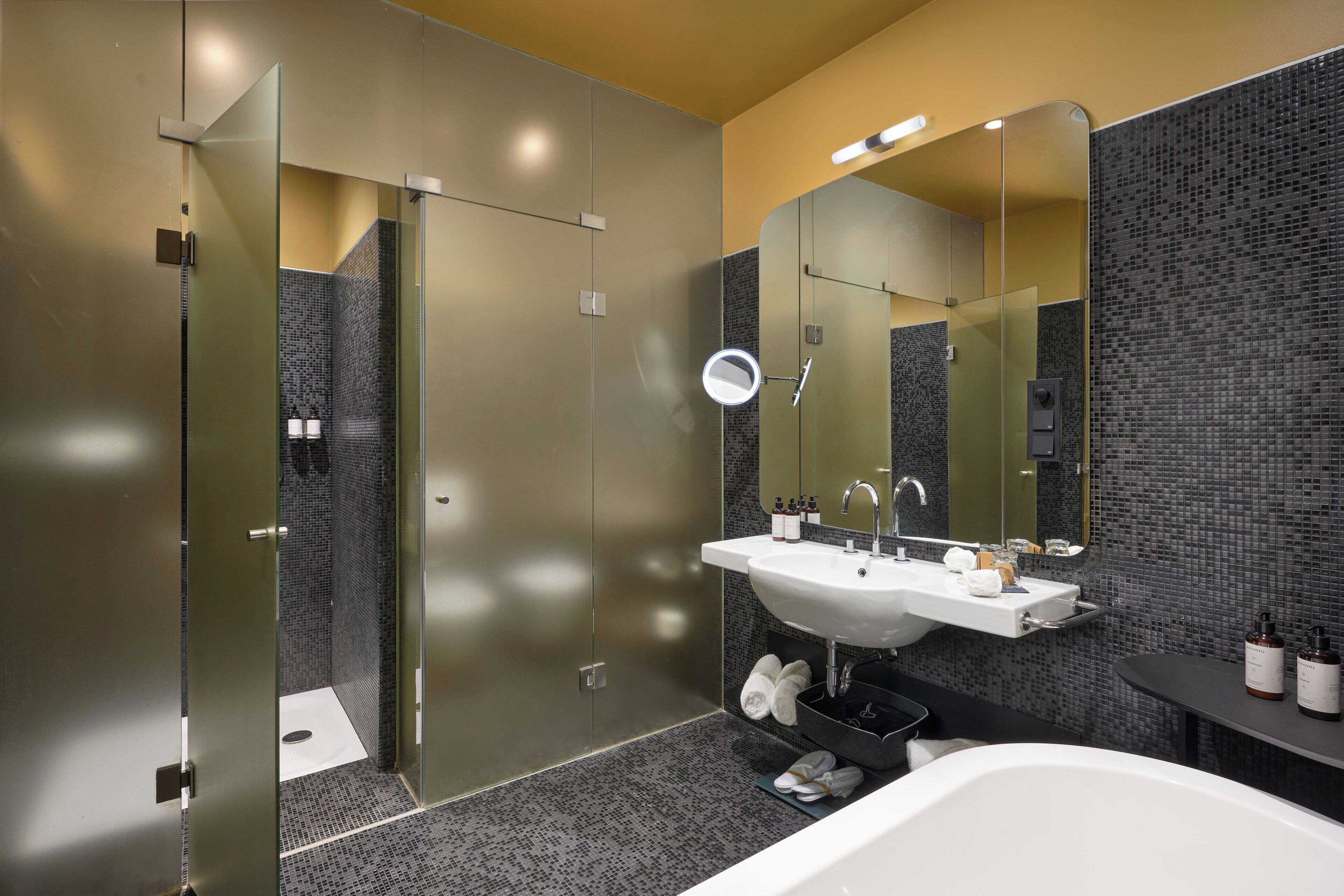 A modern bathroom with a large mirror, a sink, and a bathtub.