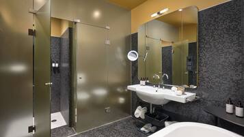 A modern bathroom with a large mirror, a sink, and a bathtub.