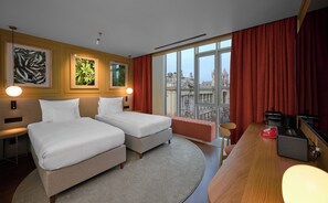 A hotel room with two beds, a desk with a computer, a view of the city, and artwork on the walls. - Verno House Budapest, Vignette Collection by IHG (Budapest)