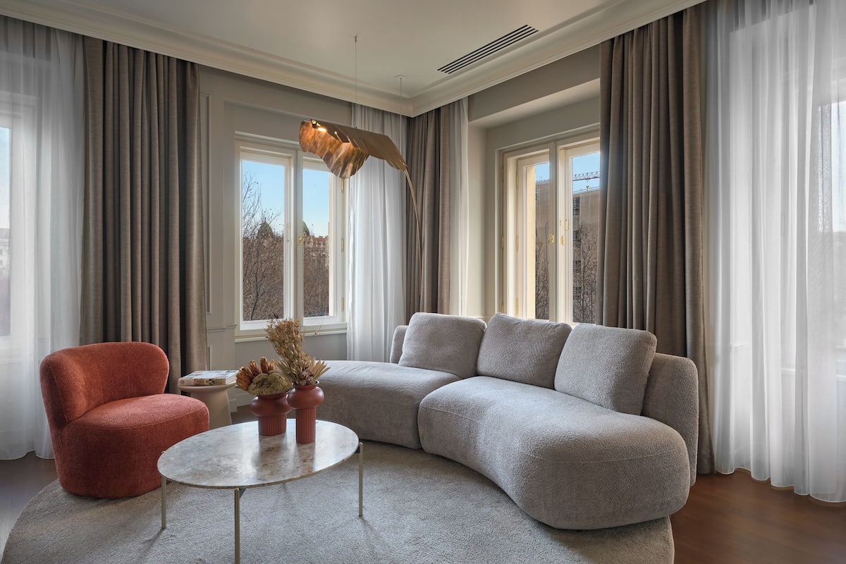 A modern living room with a grey sectional sofa, a red armchair, and a round coffee table.
