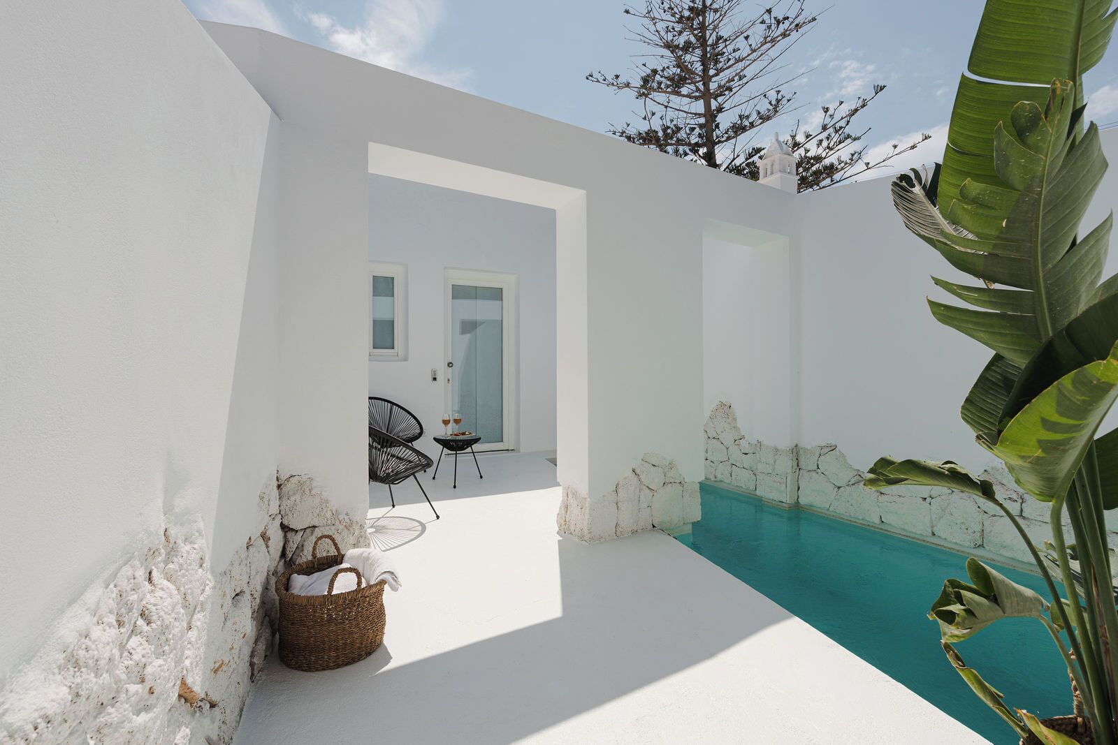 Un interior luminoso con piscina, una cesta de mimbre y una silla.