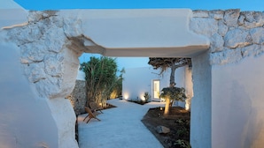 A pathway leading to a building with stone walls and a white exterior. - ANOME Mykonos (Mykonos)