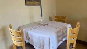 A dining table with a white tablecloth, four wooden chairs, and a candle holder. - Orchard Cabin Herefordshire Wye Valley (Ross-on-Wye)