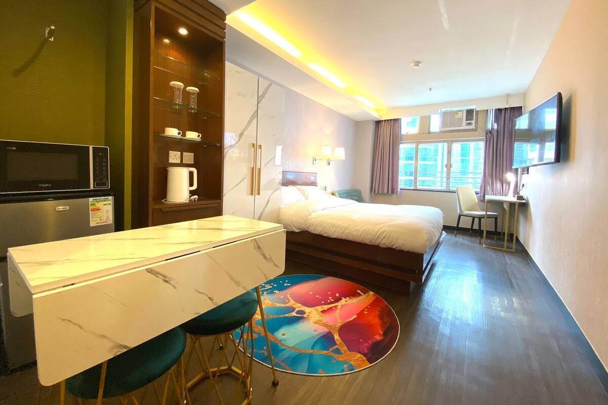 A hotel room with a bed, a desk with chairs, a microwave, a coffee maker, and a TV.