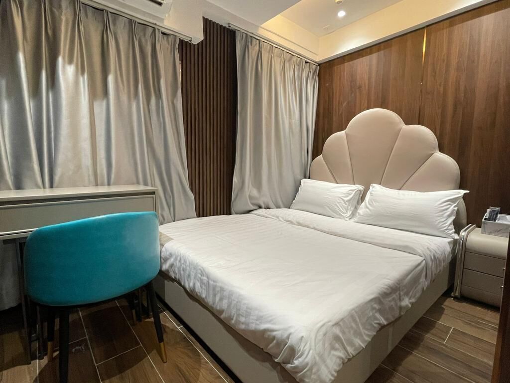 A hotel room with a bed, a desk, a chair, and a nightstand.