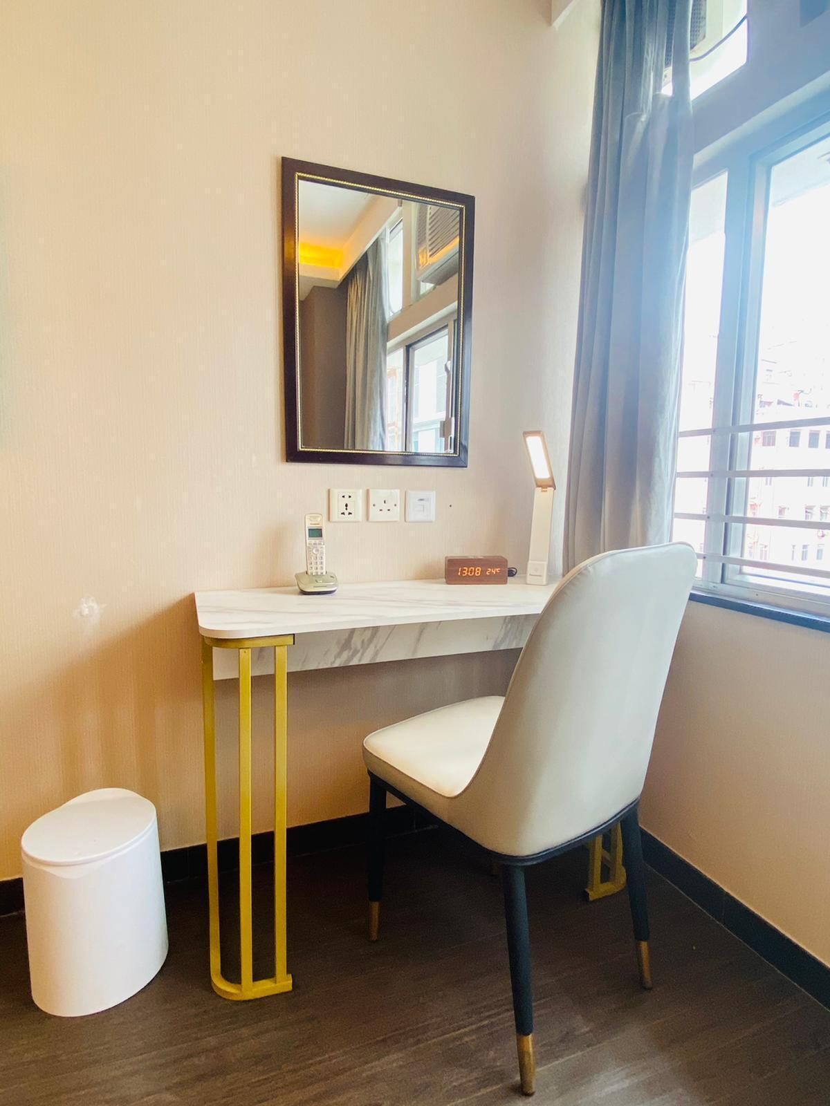 A hotel room with a desk, chair, and a window with curtains.