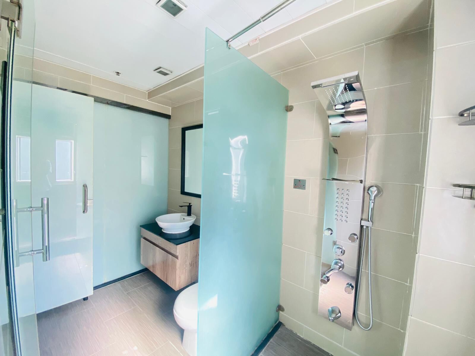 A modern bathroom with a glass shower enclosure, a white sink, and a toilet.