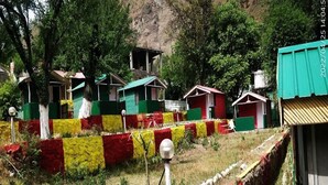 A rural setting with small, colorful houses, a grassy area, and a mountainous backdrop.