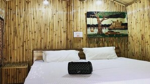 A room with a bed, a bench, and a painting on the wall.