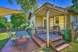 Relax on the covered patio, surrounded by lush greenery, with a round table and comfortable seating for four.