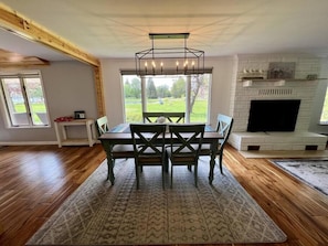 A dining area with a table and chairs, a fireplace, and a view through large windows.