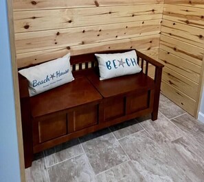 A wooden bench with two pillows, one labeled 'Beach House' and the other 'Beach.'