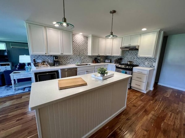 A modern kitchen with white cabinetry, a central island, and a dining area with a table and chairs.