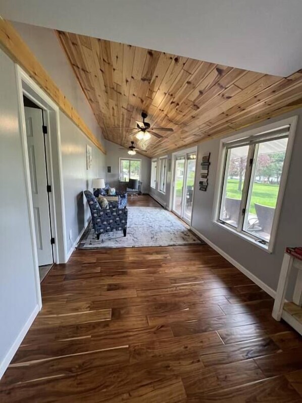 A hallway with wooden flooring, a ceiling fan, and large windows. - Sunshine Cove (Lewiston)