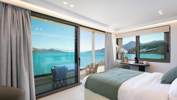 Une chambre moderne avec un grand lit, un bureau avec vue et une chaise près de la fenêtre.