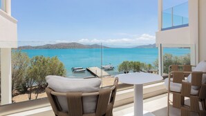 Un balcon donnant sur une mer calme, une jetée avec des bateaux et des meubles en osier.