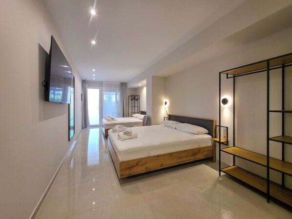 A modern hotel room with a large bed, a TV mounted on the wall, and a wardrobe with a mirror. - Lucia Hotel Paralia (Katerini)