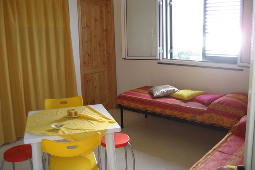 A small room with a bed, a table with chairs, and a window.