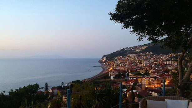 A coastal town at dusk with a view of the sea and a chair overlooking the area. - Spisidda House - Lipari Studio - Near Gioiosa Marea (Zappardino)