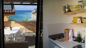 A kitchen with a view of the ocean, a dining area with chairs, and a table. - Spisidda House - Lipari Studio - Near Gioiosa Marea (Zappardino)