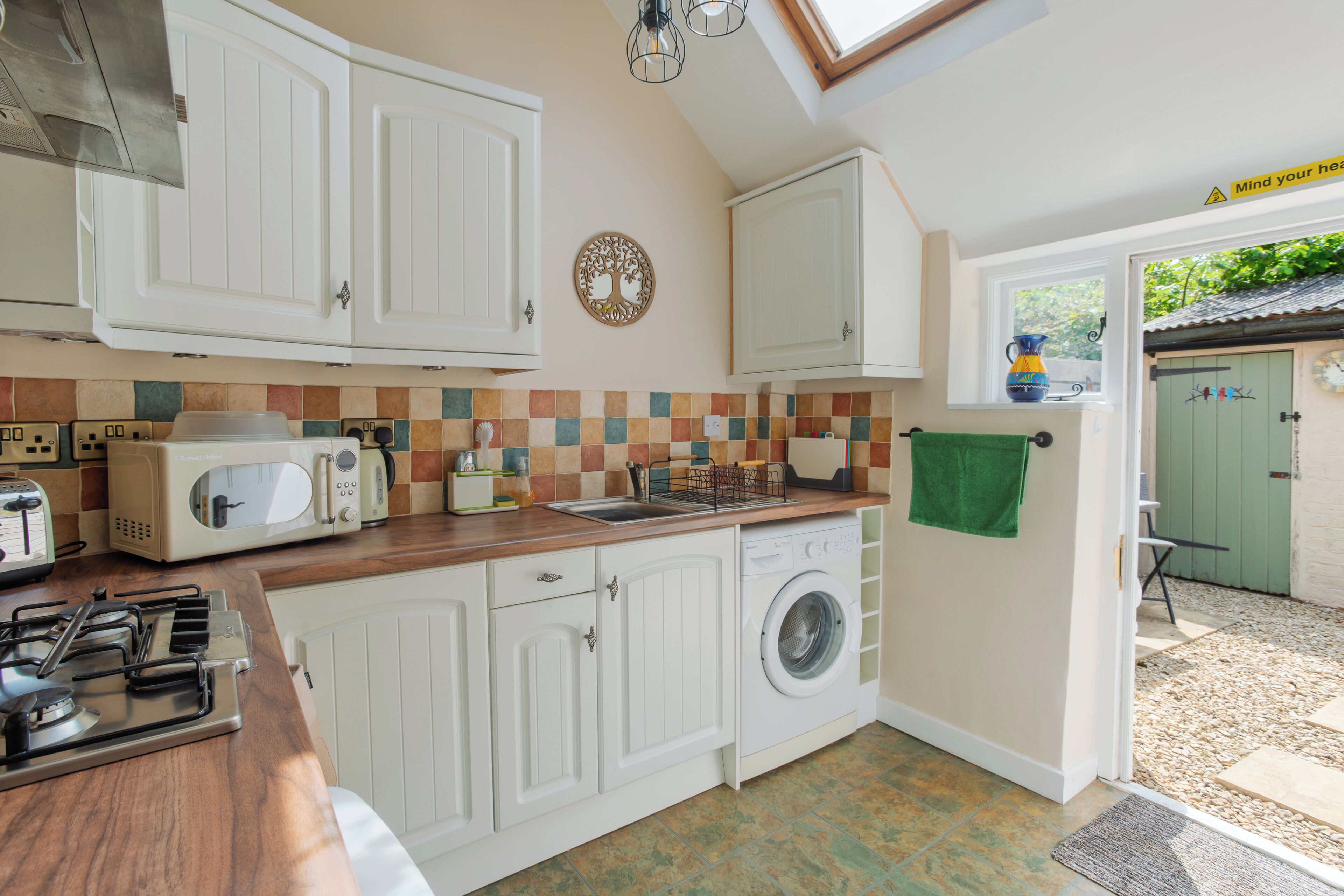 A compact kitchen with white cabinets, a microwave, a toaster, and a washing machine.