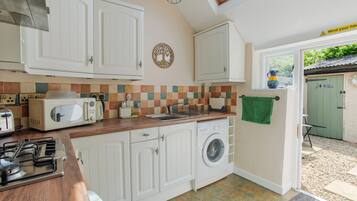 A compact kitchen with white cabinets, a microwave, a toaster, and a washing machine.