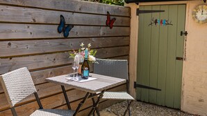 Une table en bois avec des chaises, une bouteille et des verres, sur une terrasse.