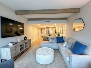 Ein modernes Wohnzimmer mit einer Couch, Hocker und einem Unterhaltungssystem.
