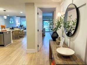 Une cuisine moderne avec un îlot central, un coin repas avec des chaises en osier et un grand miroir au mur.