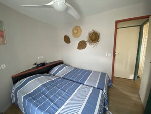 Quarto com duas camas, ventilador de teto e decorações nas paredes.