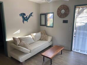 A living room with a white sofa, a wooden coffee table, and decorative wall art. - Fisherman's Island Mas (Le Barcarès)