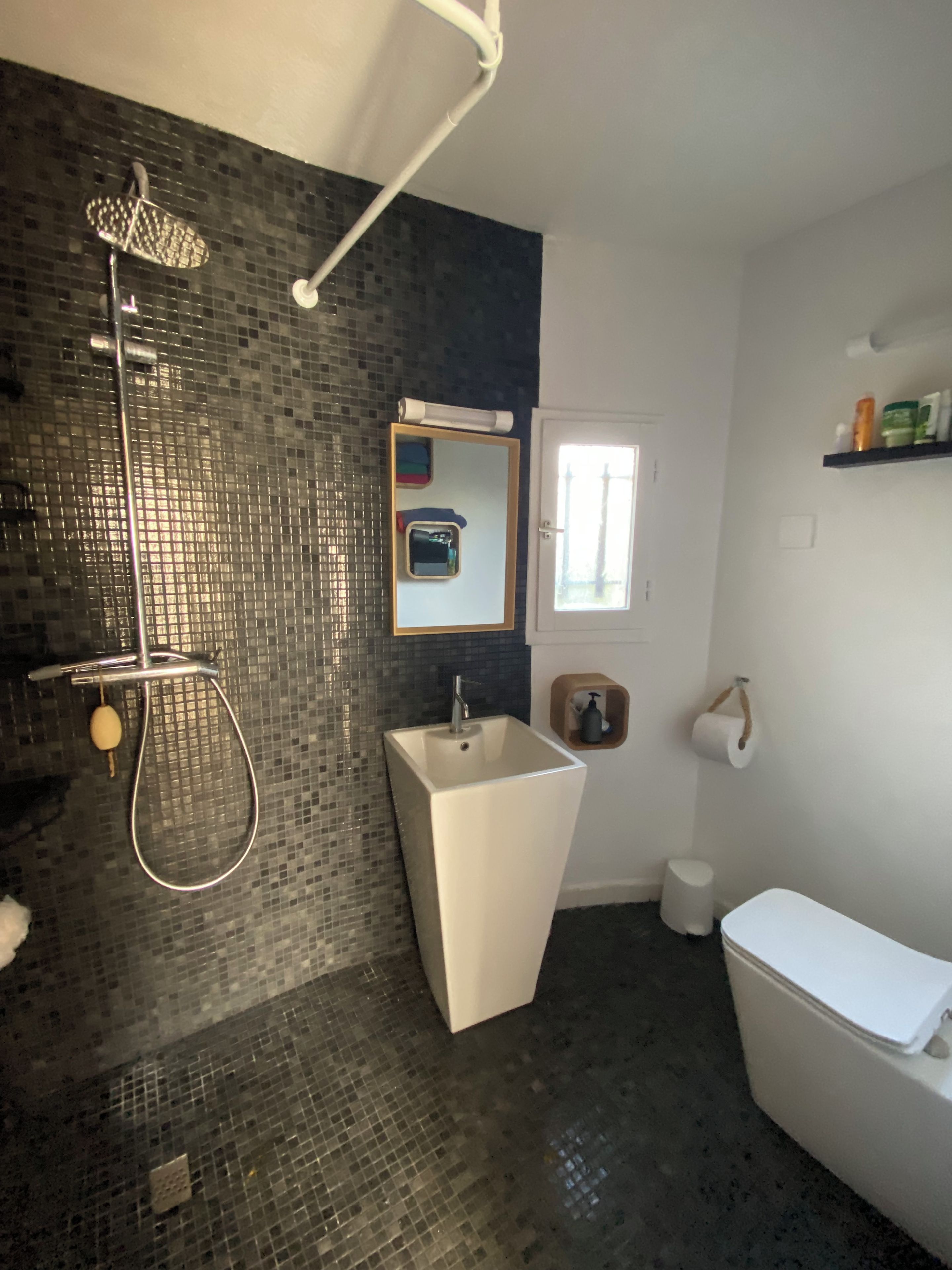 Un baño con ducha, lavamanos, inodoro y espejo.