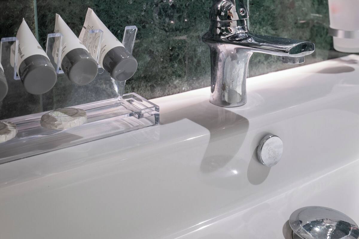 A bathroom with a white sink, a mirror, and a green tiled wall.