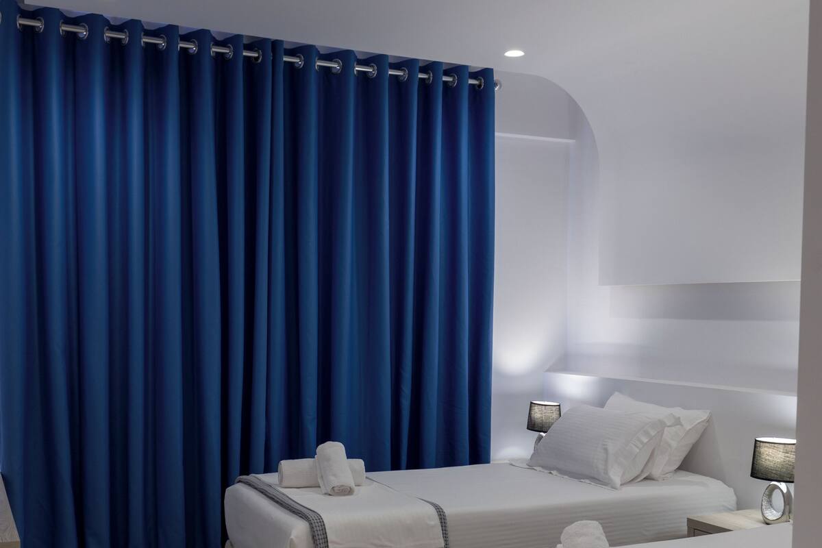 A hotel room with two beds, a large window, and a curtain.