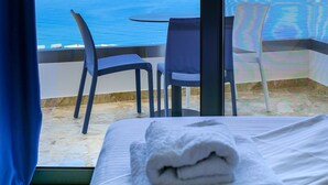 Una habitación con una cama, una mesa y dos sillas. La habitación tiene vista al mar.