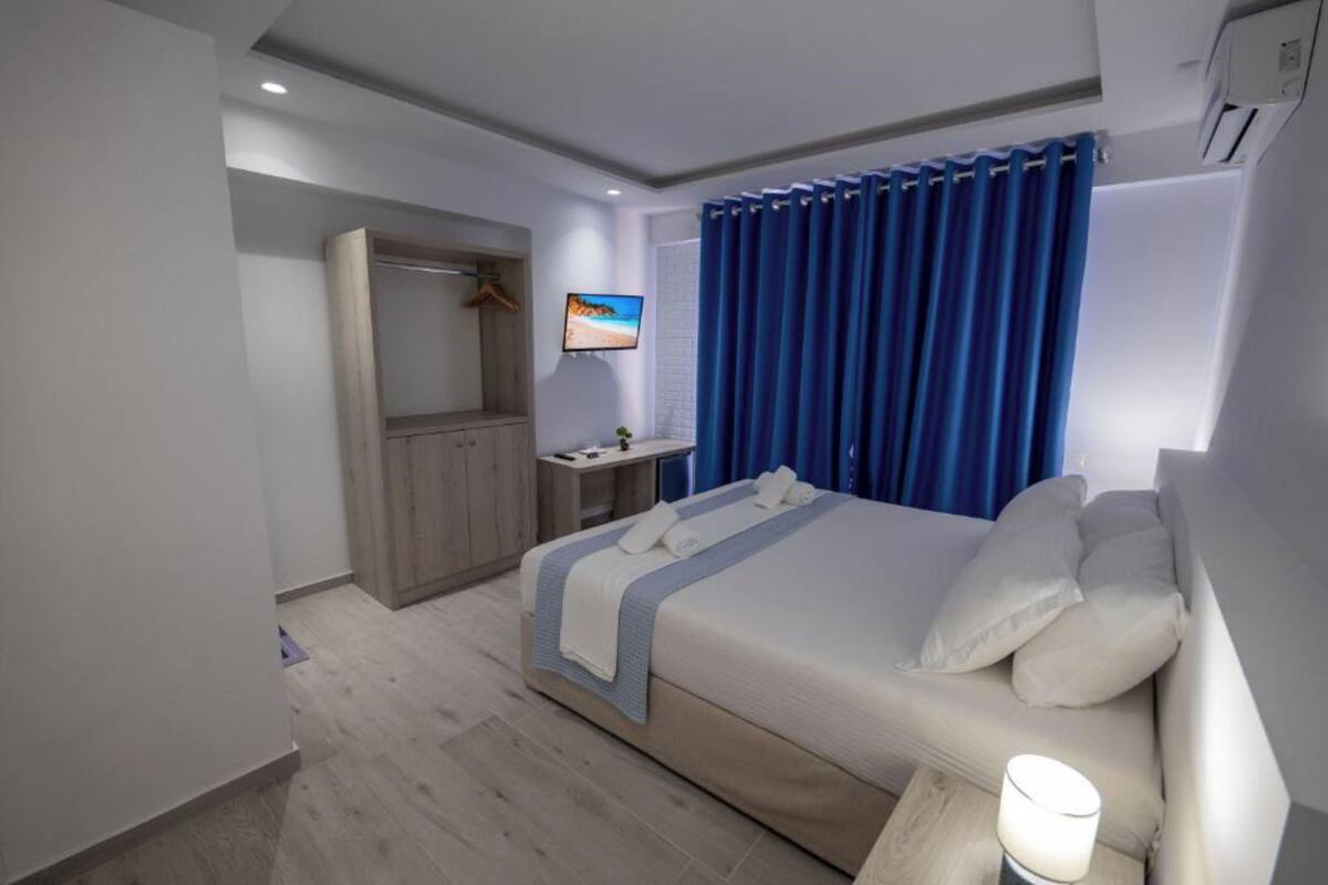 A hotel room with a bed, a TV, a desk, and a wardrobe.