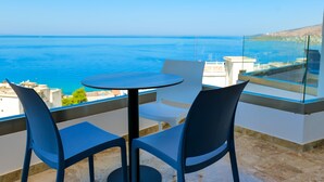 Un balcón con una mesa redonda y dos sillas, con vistas a la costa.