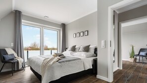 Een moderne slaapkamer met een groot bed, een stoel en uitzicht op de omgeving.