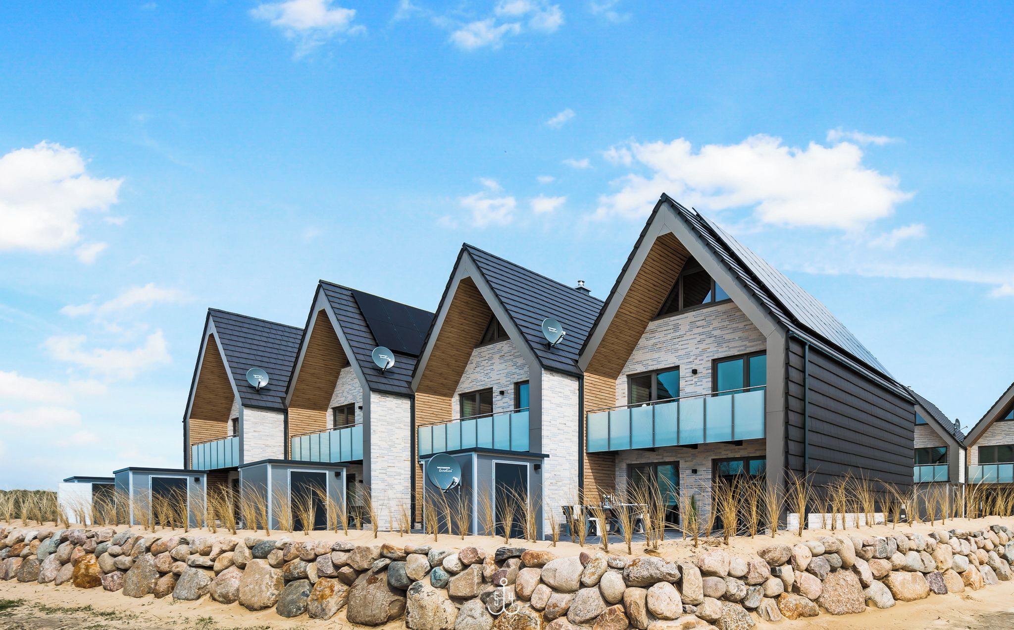 Un bâtiment moderne comprenant plusieurs logements, doté d’une façade en pierre et d’un toit en pente.