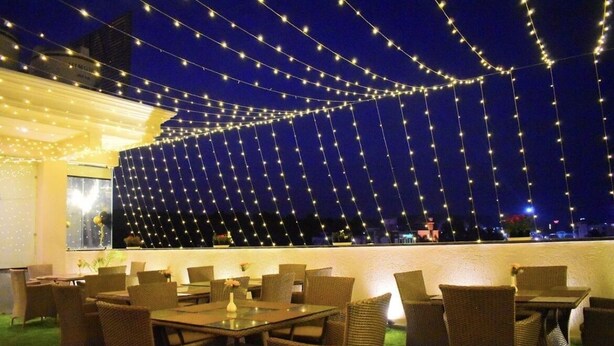 Un área de comedor al aire libre con mobiliario de mimbre y luces colgantes.