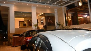 Un edificio moderno con techo de vidrio, un restaurante y coches estacionados.