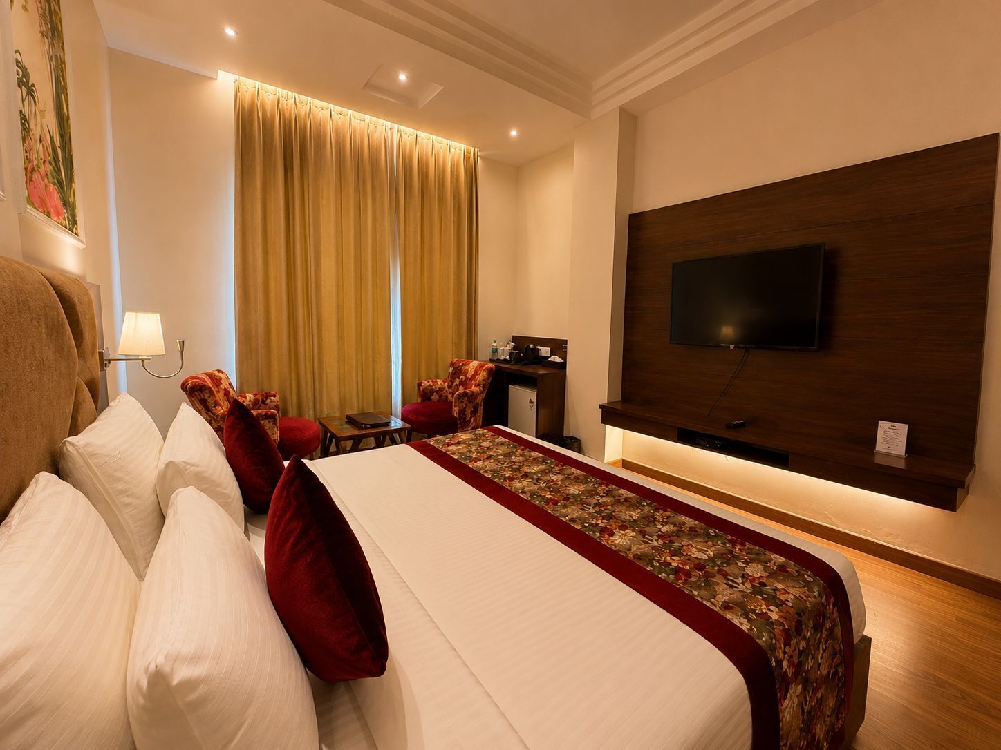 Habitación de hotel con cama, escritorio, televisor y ventana con cortinas.