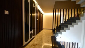 Un interior moderno con una escalera, una pared de madera con círculos recortados y una lámpara.
