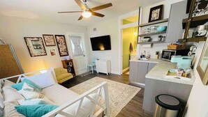 Un espace de vie compact comprenant un lit, une kitchenette et un téléviseur.