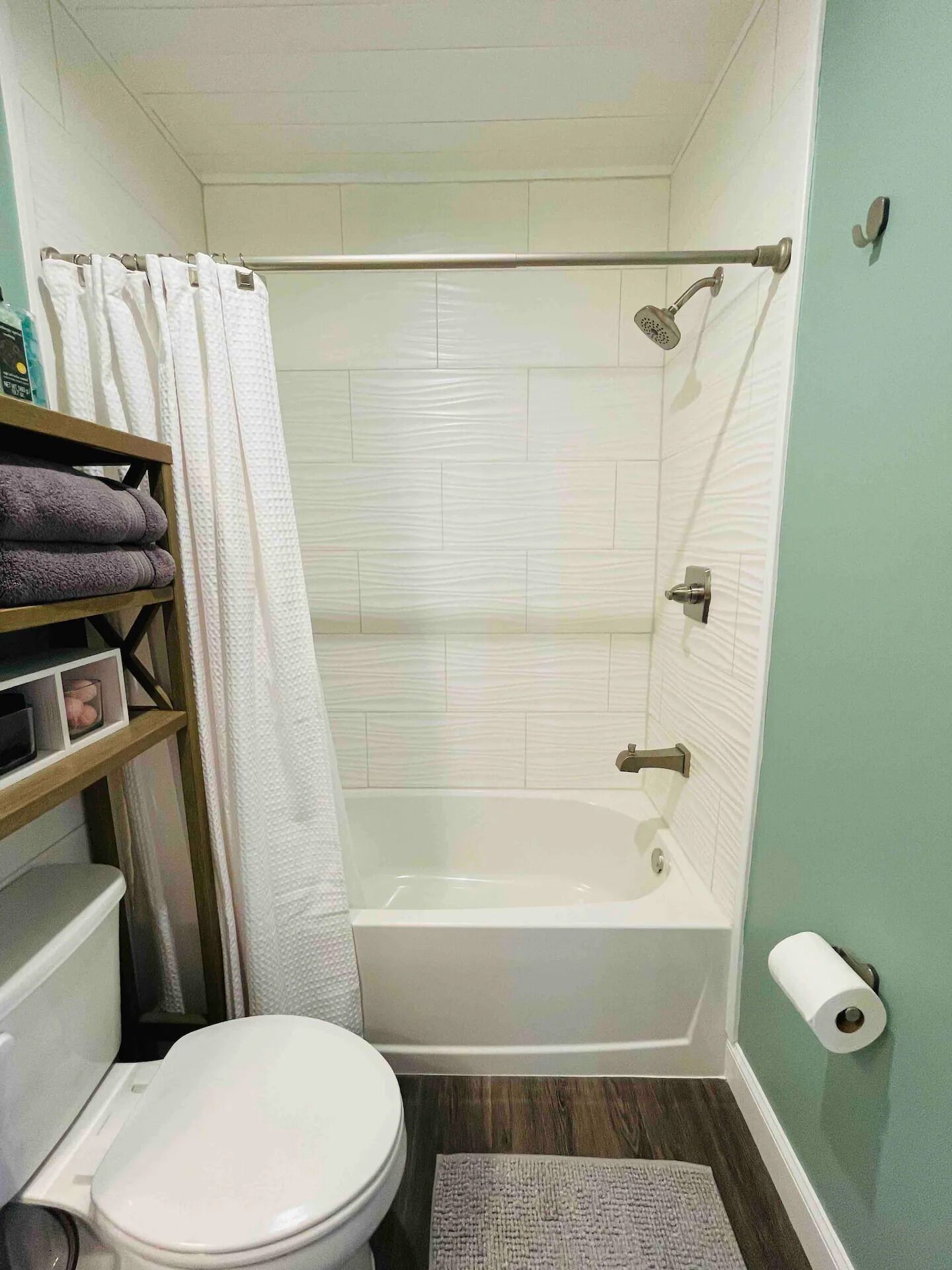 Ein Badezimmer mit Toilette, Badewanne, Dusche und Ablagefläche für Handtücher.