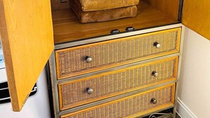 Une armoire en bois avec un espace pour suspendre les vêtements et trois tiroirs.