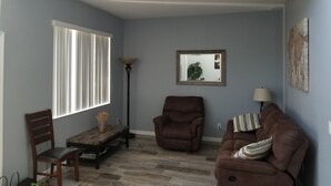Ein Wohnzimmer mit einer Couch, einem Sessel und einem Tisch mit einer Vase.