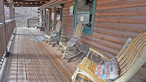 Eine Holzhütte mit Veranda, ausgestattet mit Schaukelstühlen und einem Tisch.