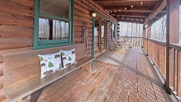 Eine Holzhütte mit einer Veranda, Bänken, Schaukelstühlen und Lichterketten.